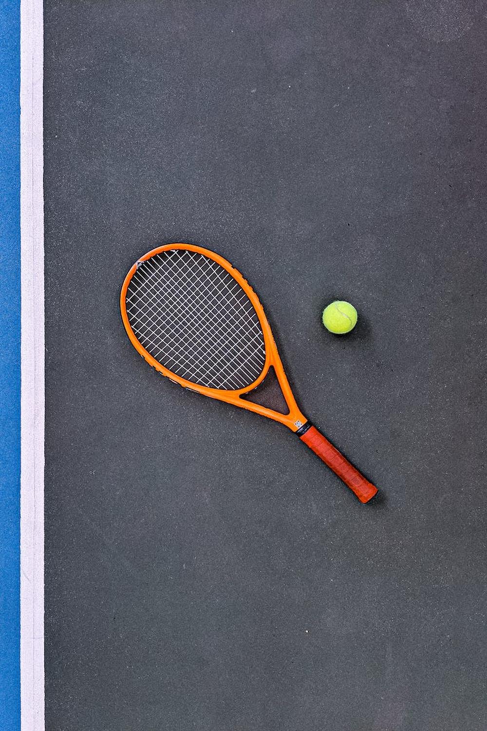 orange_tennis_racket_beside_green_tennis_ball